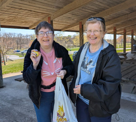 Star DSP Karen and a person supported hold easter eggs while standing at a park pavilion 